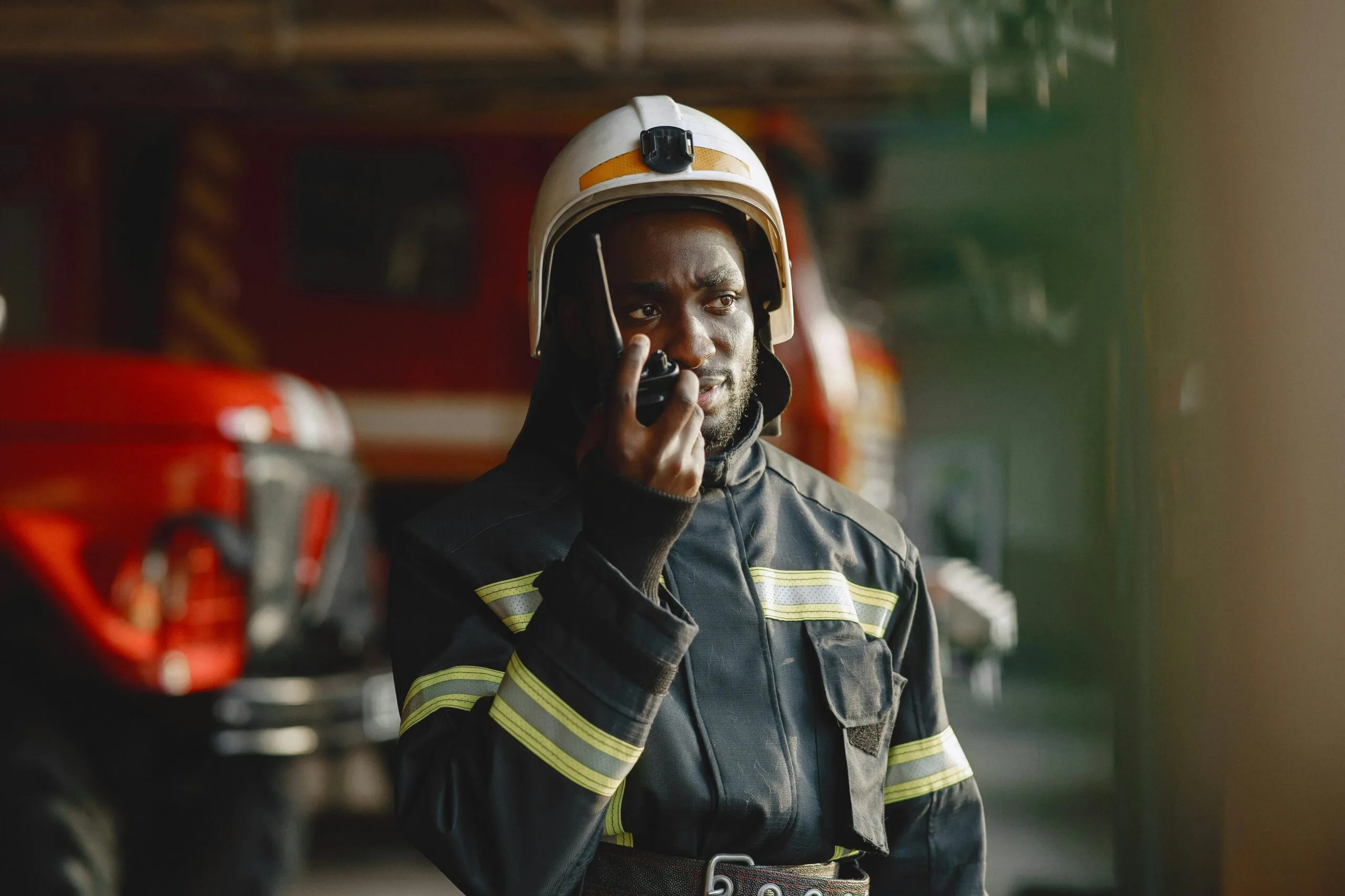 African American firefighter in uniform using walkie talkie, focused on communication.